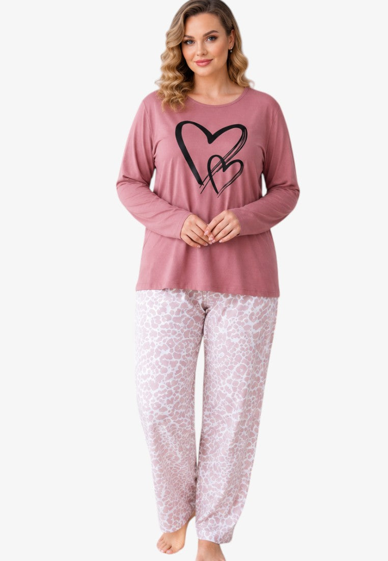 Lifestyle shot of a plus size cotton pajama set in pink with heart print on a model.
