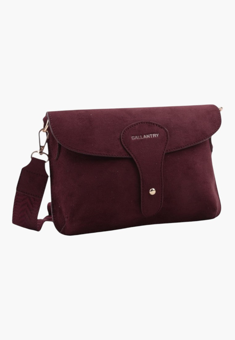 Szczegółowy widok burgundowej torebki listonoszki z zamkiem na klapkę i złotymi akcentami.