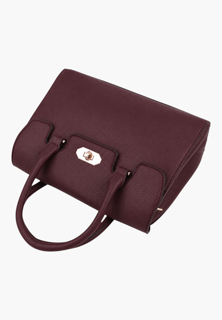 Detail close-up of a burgundy handbag showcasing top handles and gold hardware on a white background.