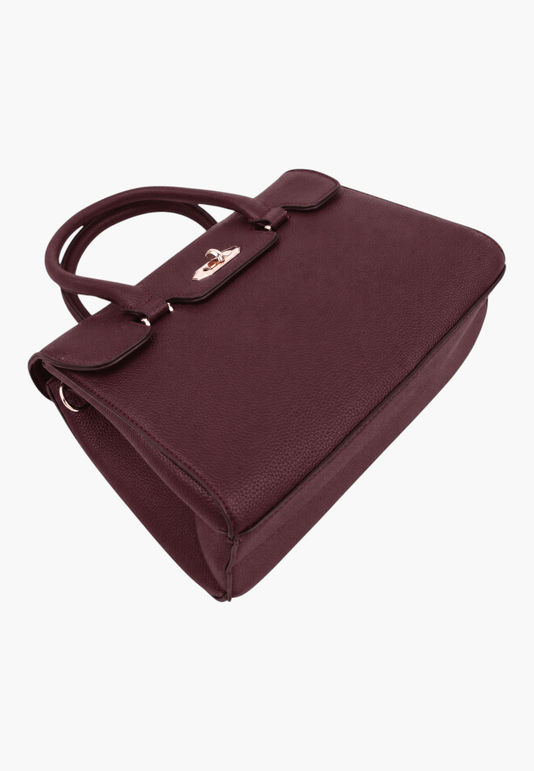 Side view of a structured burgundy handbag with top handles on a white background.