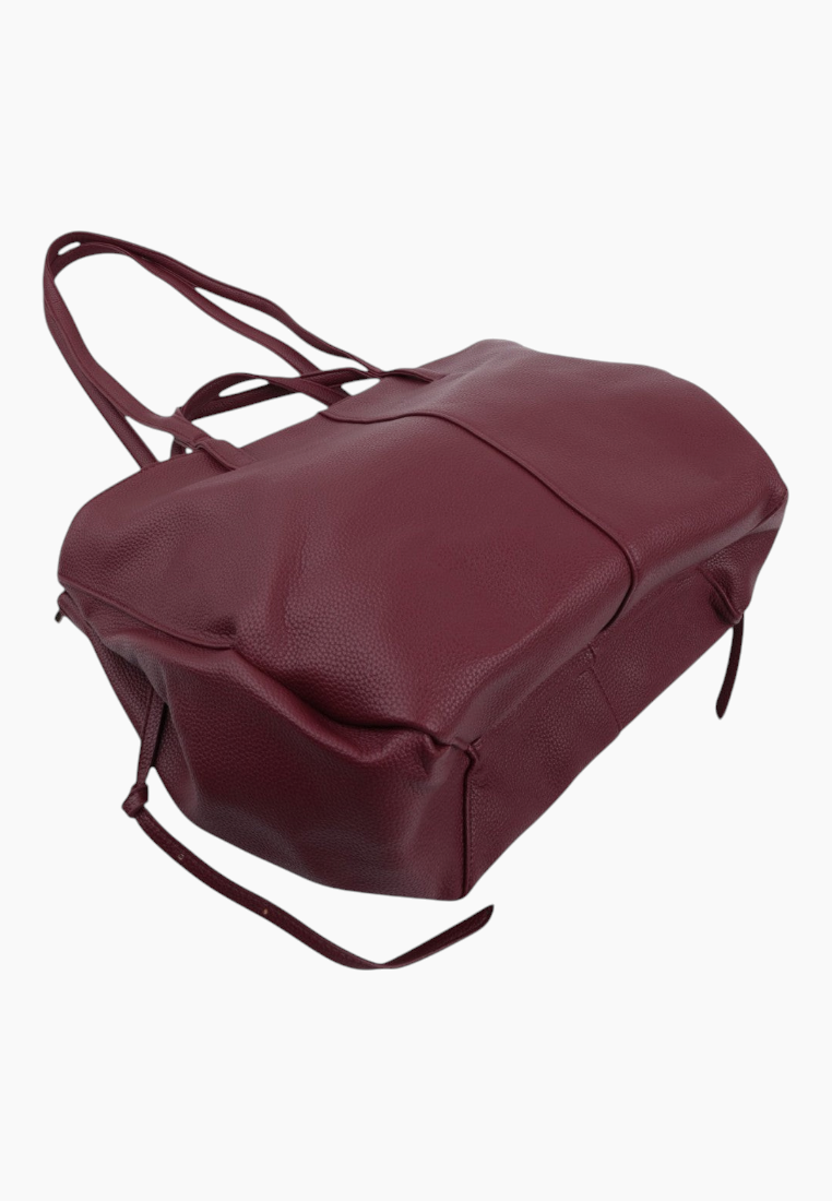 Detail shot of the top of a burgundy handbag with two handles and spacious design.