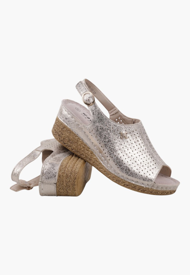 Lifestyle shot of wedge sandals in silver and beige with an open toe and slingback strap.