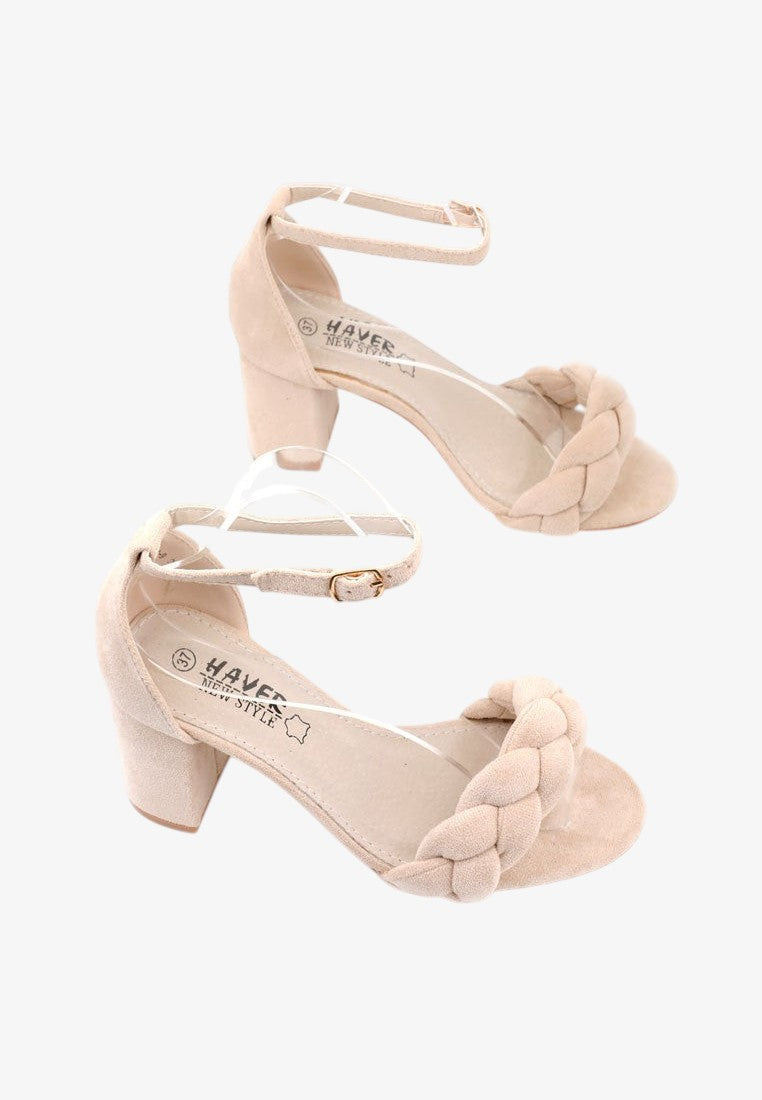 Beżowe buty na wysokim obcasie, zbliżenie na pleciony pasek.