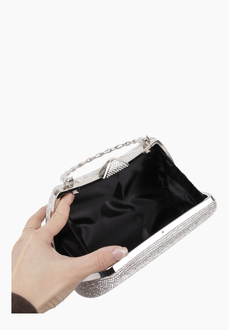 Detail of the interior of the silver clutch bag with black lining and spacious interior.