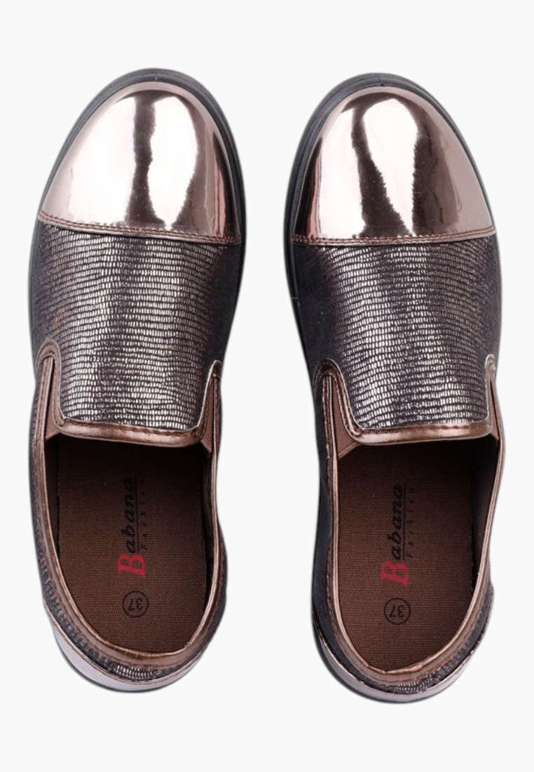 Lifestyle image of brown slip-on shoes featuring metallic toe details.