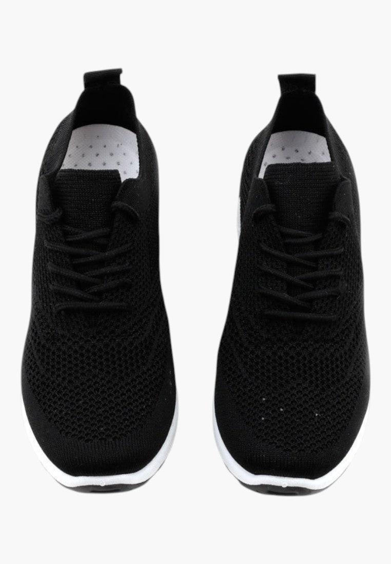 Zbliżenie na detale czarnych sneakersów damskich na koturnie z elastycznym dopasowaniem.