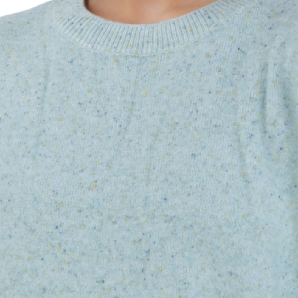 Detail view of the light blue sweater highlighting the crew neck and textured fabric.