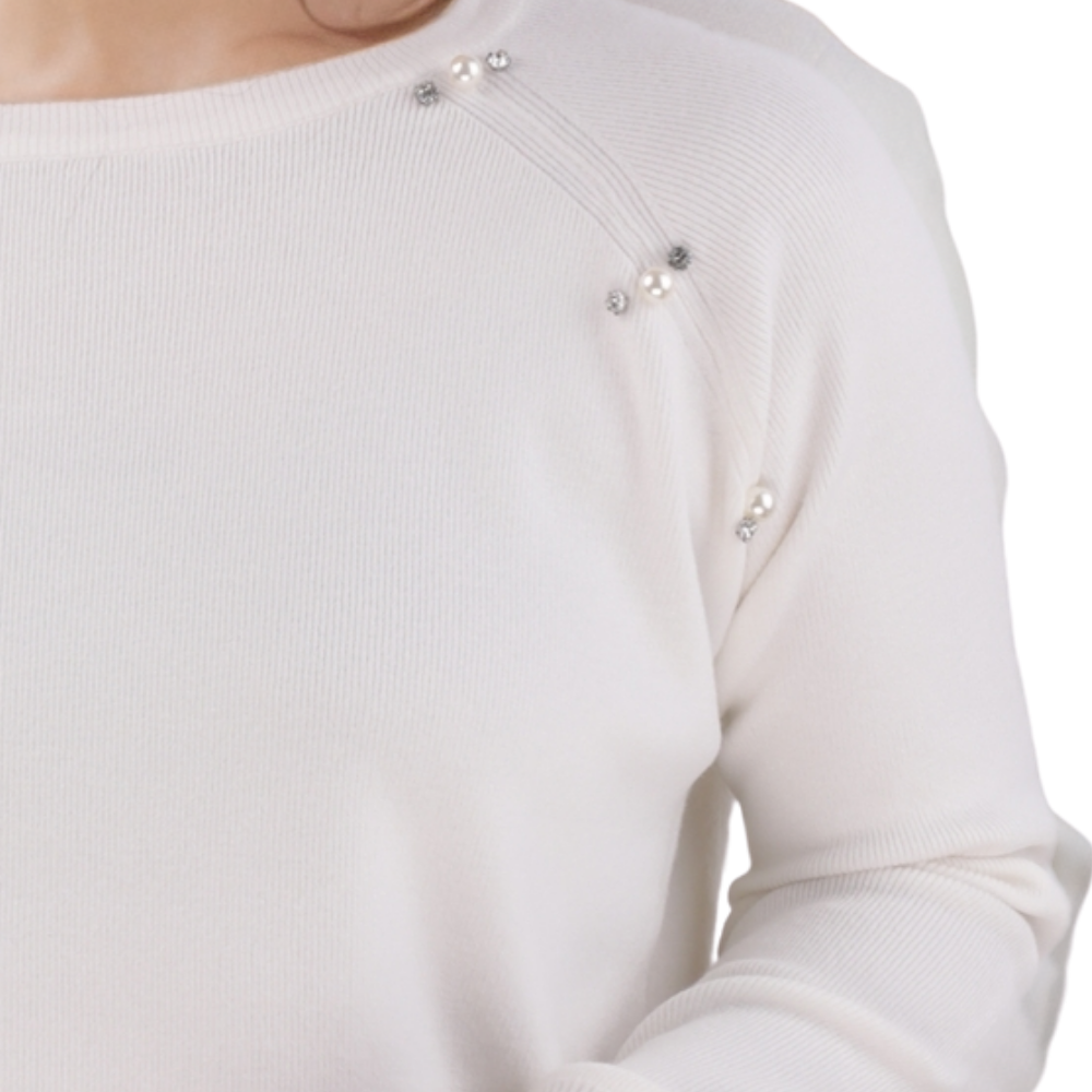 Detail close-up of the white sweater showing snap buttons and long sleeves.
