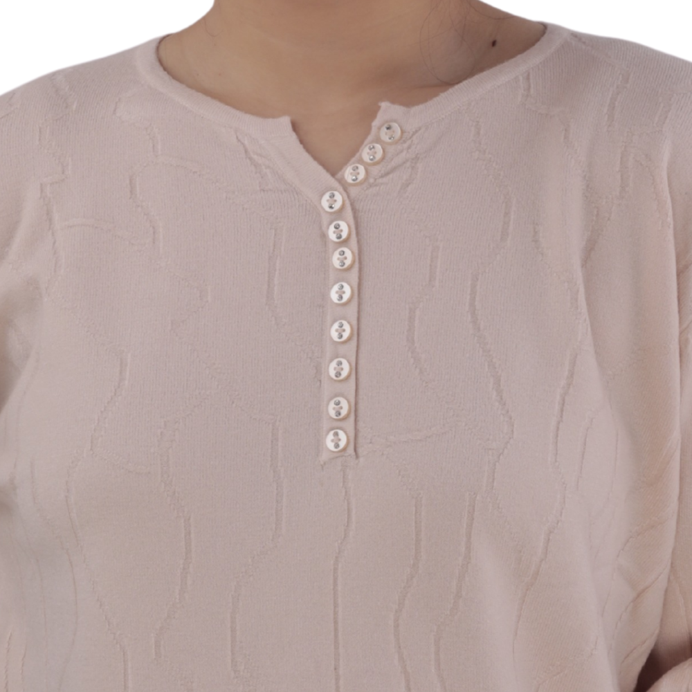 Close-up detail of the light pink top with button detail and textured pattern.