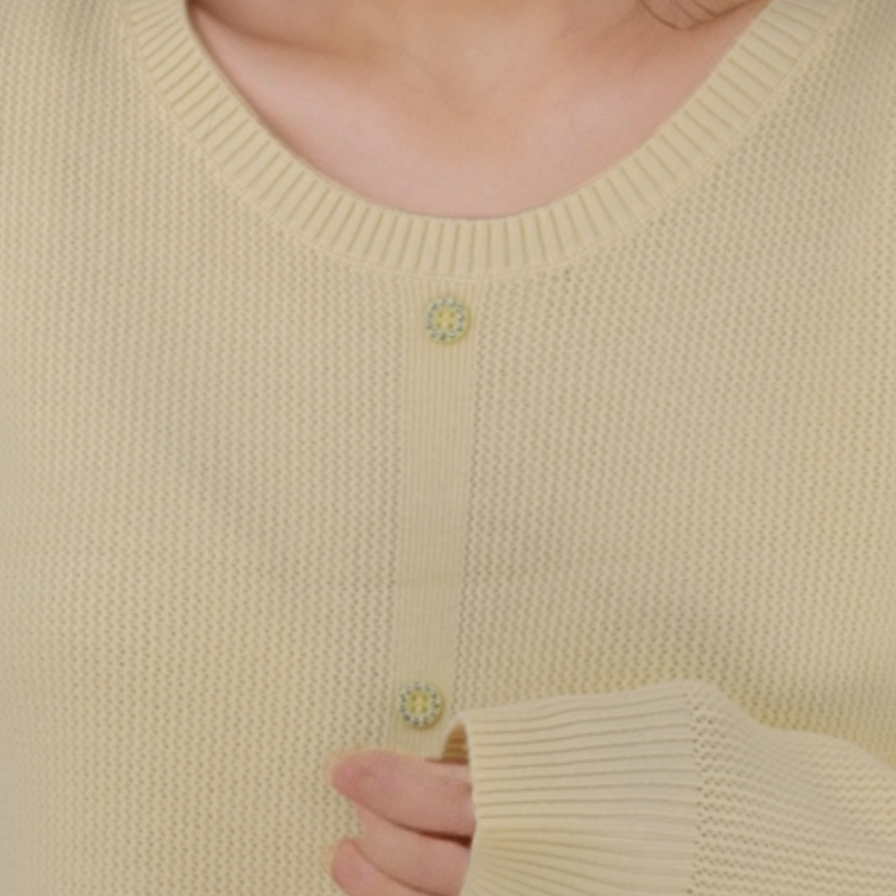 Close-up detail of the żółty sweter damski showing button detail and soft fabric.