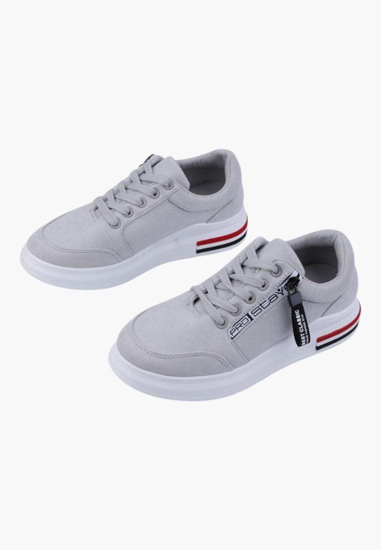 Zbliżenie na szare sneakersy z paskiem na podeszwie.