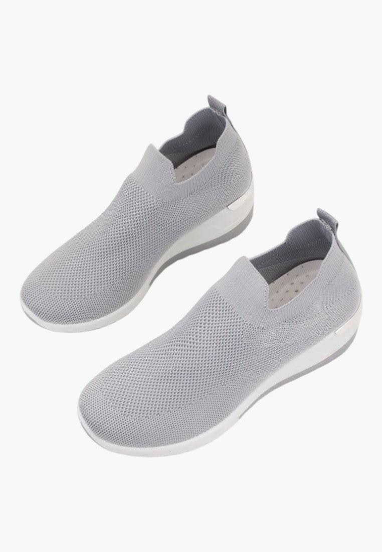 Górny widok szarych sneakersów damskich z rozciągliwego materiału.