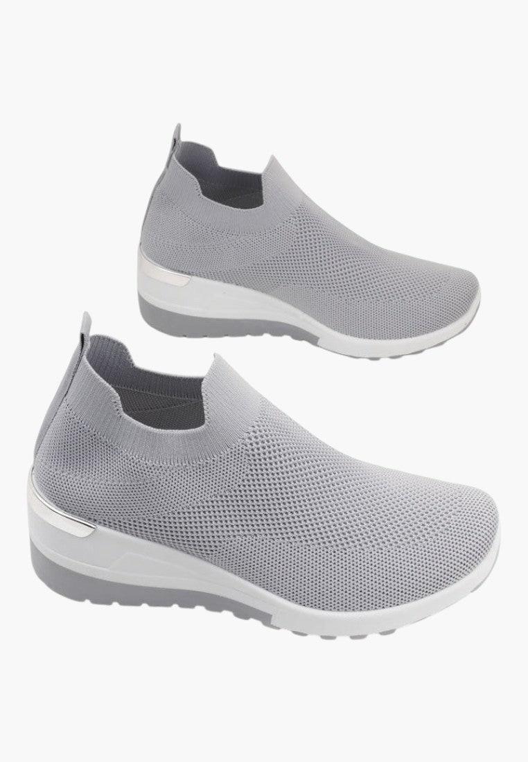 Zbliżenie na teksturowany materiał szarych sneakersów damskich.