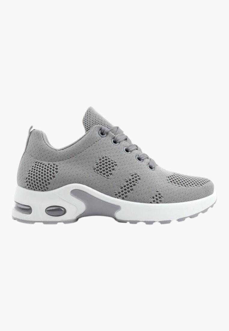 Widok z boku szarych sportowych sneakersów z siateczkowym wierzchem.