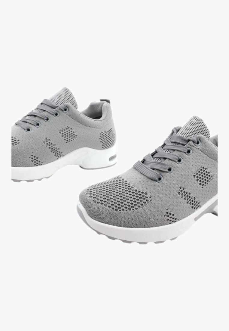 Zbliżenie na teksturowany materiał szarych sportowych sneakersów.