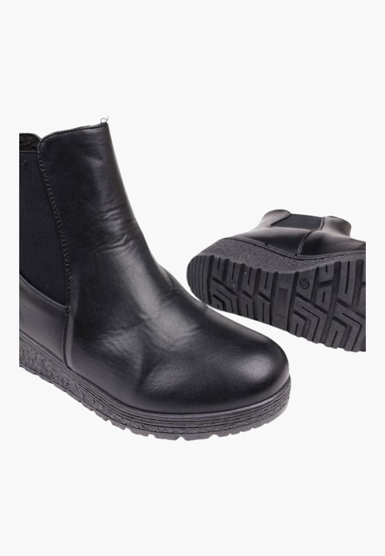 Close-up detail of black ankle boots featuring textured sole and rounded toe.