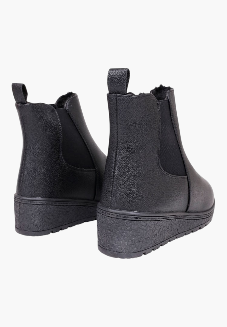 Back view of black ankle boots with elastic side panels and chunky sole on a white background.