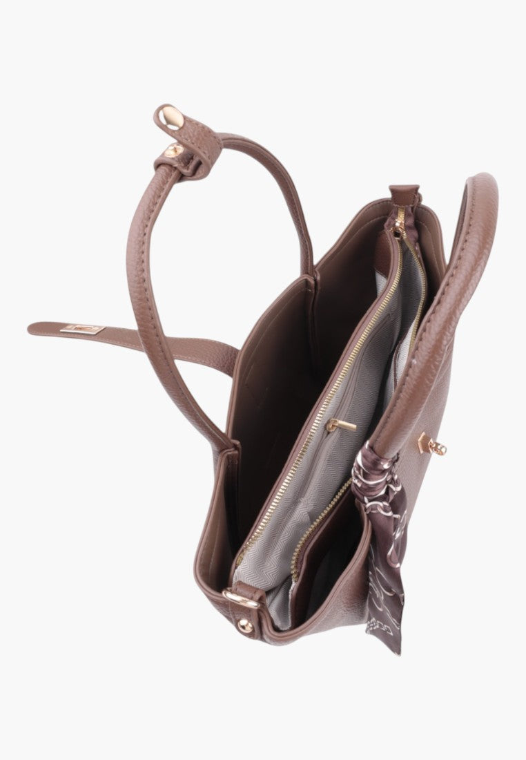 Lifestyle shot of taupe faux leather shopper bag with two zippered compartments and scarf detail.