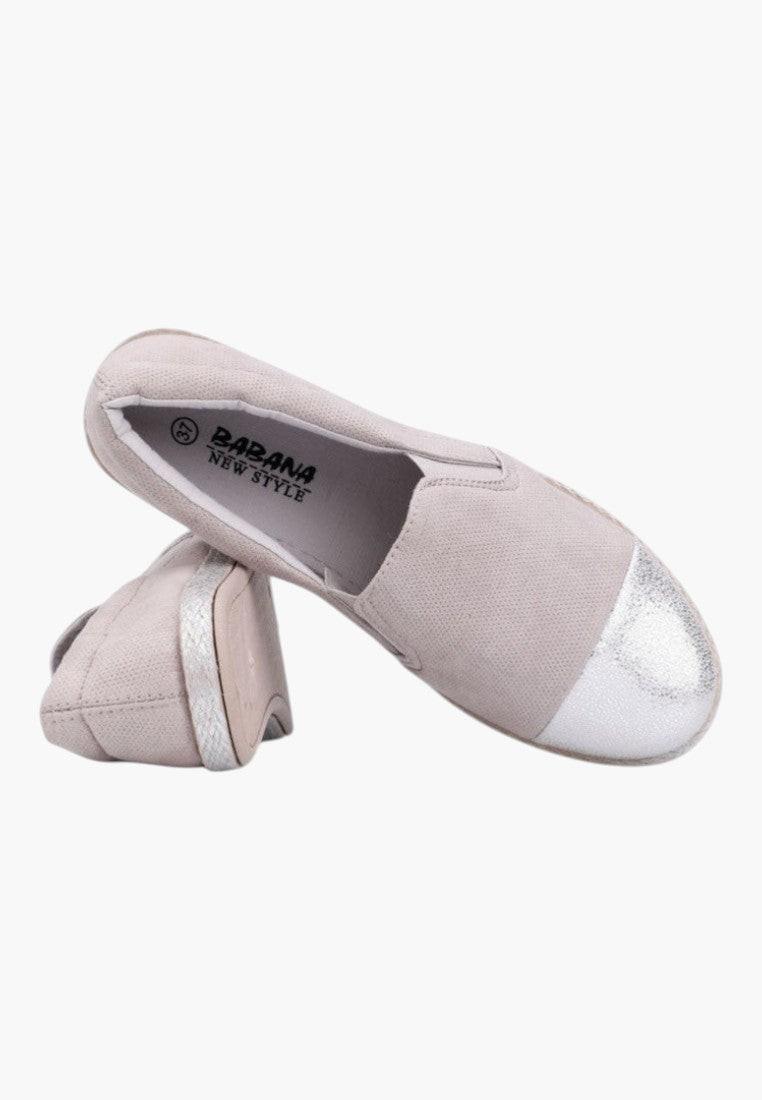 Close-up detail of the beige slip-on shoes highlighting the shiny toe cap.