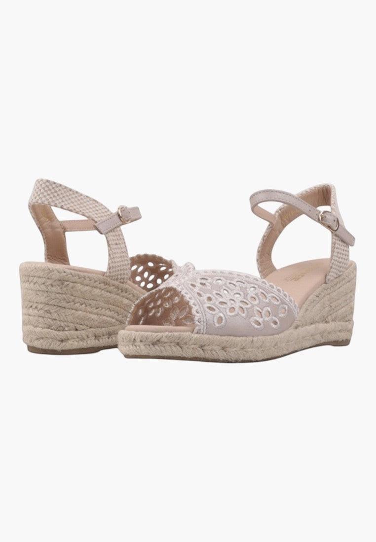 Side view of white and beige wedge sandals with open toe and woven design on a white background