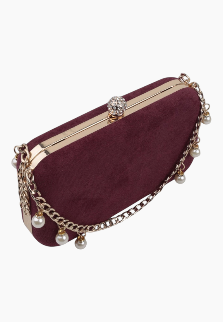 Detail view of the burgundy clutch bag with chain strap and pearl accents.