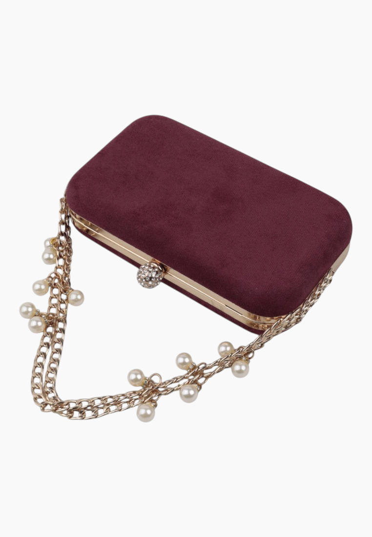 Detail view of the burgundy clutch purse highlighting chain strap and pearl embellishments.