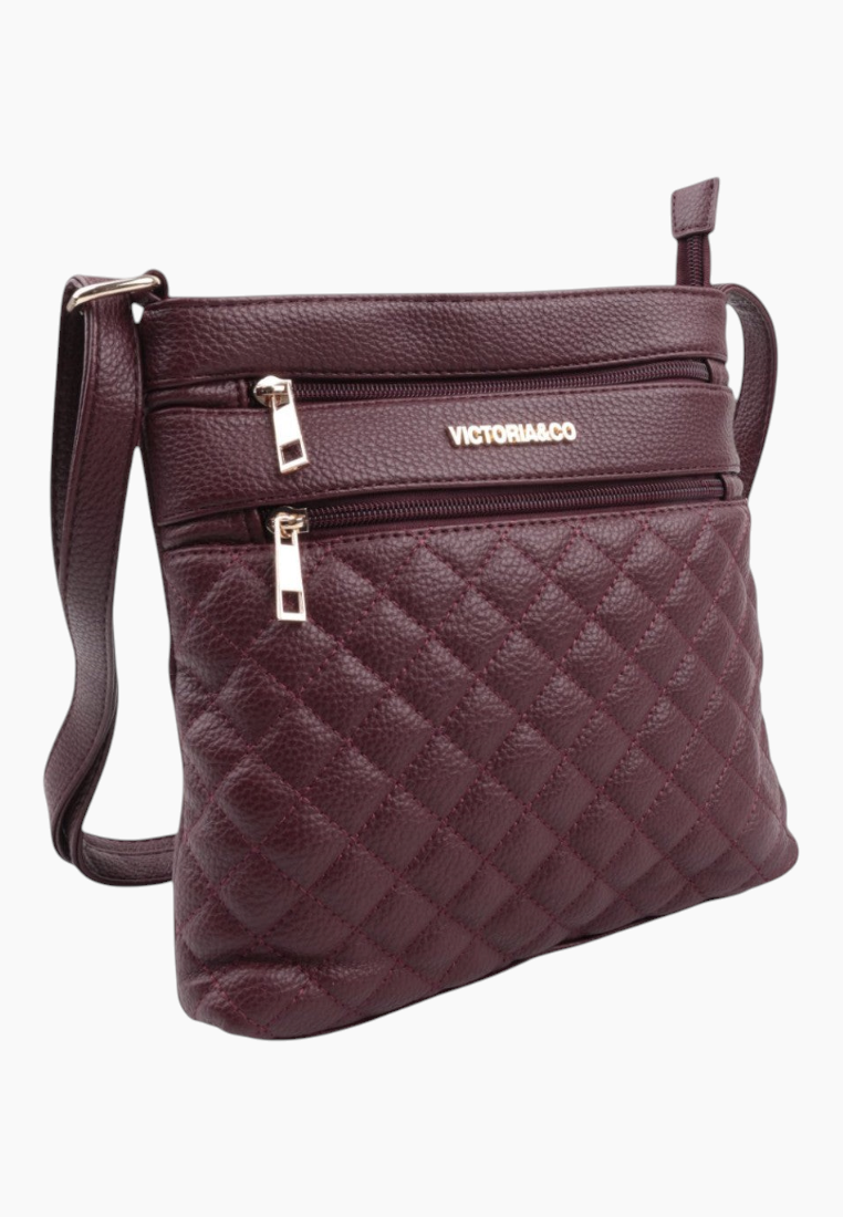 Detail of burgundy quilted handbag with zipper pockets on a white background