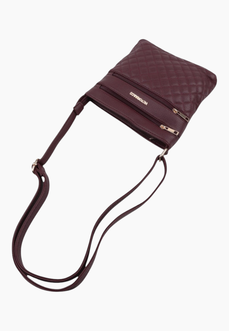 Side view of burgundy quilted handbag showing zipper pocket and adjustable strap